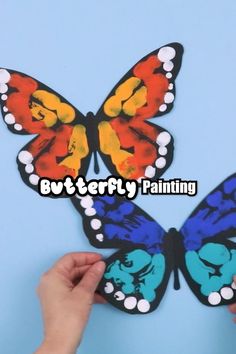 the butterfly painting is being held up by someone's hand