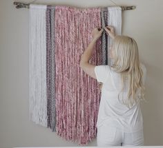 a woman is working on a wall hanging project with yarn and wood dows in front of her