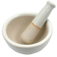 a white mortar and pestle in a small bowl on a white background with clippings