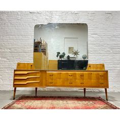 an old dresser with a large mirror on it's side and a rug in front of it