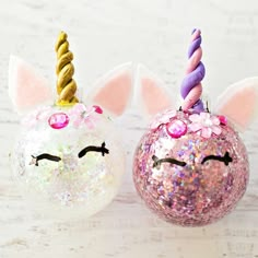 two unicorn - like ornaments with glitter on them are sitting in front of each other