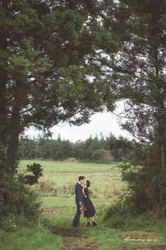 an engaged couple standing in the middle of a forest