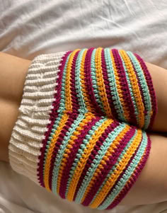 a woman's arm is covered in multicolored crochet