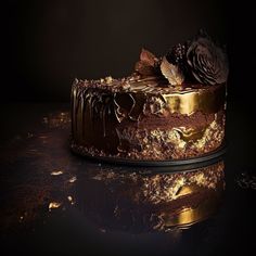 a cake with chocolate frosting and flowers on top is sitting on a shiny surface