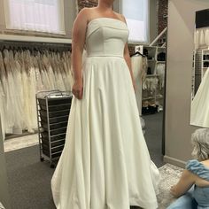 a woman standing in front of a mirror wearing a white dress