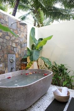 a bathtub sitting on top of a white floor next to a lush green tree