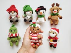 there are many small crocheted animals on the table, one is holding an ornament