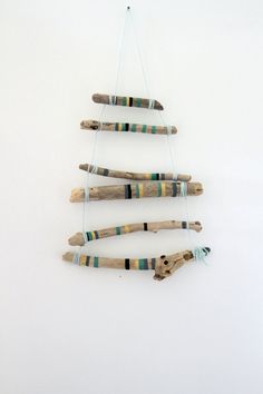 three pieces of driftwood are hanging on the wall with strings attached to them, and one piece is made out of wood sticks