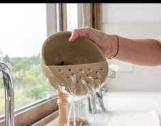 a person is pouring water from a faucet into a sink