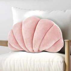 a pink pillow sitting on top of a white chair