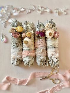 three rolls of fabric with flowers on them and some scissors next to it, all wrapped in pink ribbon