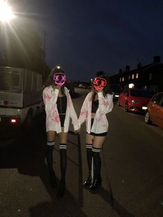 two young women in short skirts and knee high boots are standing on the street at night