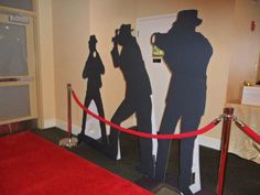 three silhouettes of people standing in front of a red carpeted area with a rope