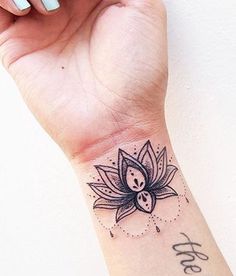 a woman's wrist with a lotus tattoo on the left side of her arm