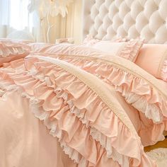 a bed with pink ruffled sheets and pillows