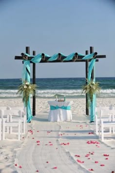 an outdoor ceremony setup on the beach with blue and white draping, flowers and chairs