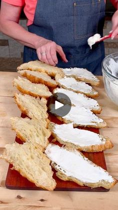 a woman in an apron is spreading cream cheese on bread