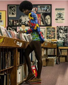 a woman standing on top of a book shelf in a room filled with books and records