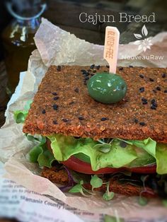 a sandwich with lettuce and tomato on it sitting on top of some paper