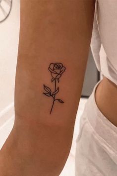 a woman's arm with a small rose tattoo on the left side of her arm