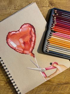 colored pencils and crayons are next to a drawing of a heart on a piece of paper