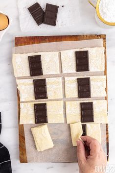 someone is placing chocolate squares on top of each other to make an appetizer