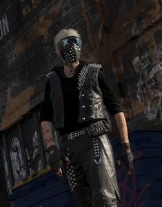 a man in leather clothes standing next to a brick building with graffiti on the walls