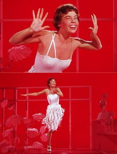 a woman in white dress standing on stage with her arms out and hands up to the side