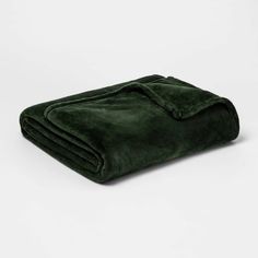 a green blanket folded on top of a white surface