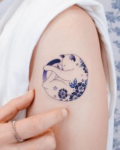 a woman's arm with a blue and white flowered tattoo on her left shoulder