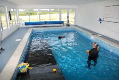 an indoor swimming pool with two people in it and one person on the other side