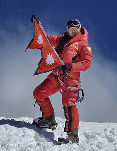 a man holding a canadian flag on top of a snow covered mountain