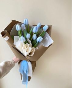 a bouquet of blue tulips in a brown paper wrapper with someone holding it