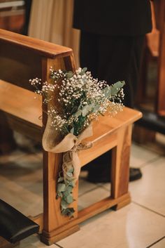 a bouquet of baby's breath sits on the back of a wooden bench at a wedding