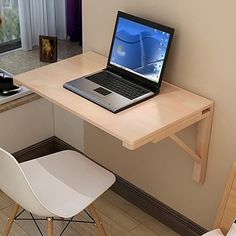 a laptop computer sitting on top of a wooden desk next to a white plastic chair