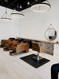 a hair salon with lots of chairs and mirrors on the wall, lights hanging from the ceiling