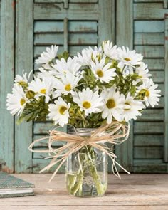 a vase filled with white daisies sitting on top of a table