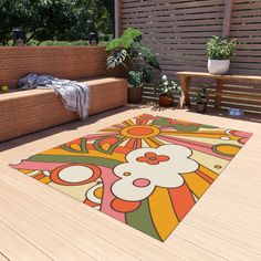 an outdoor area with wooden benches, plants and a rug on the ground in front of it