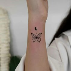 a woman's wrist with a small butterfly tattoo on the left side of her arm