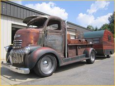 an old truck is parked in front of a building with a trailer attached to it