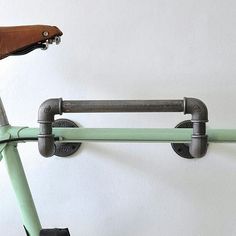 a green bike is hanging on a white wall and has two bars attached to the handlebars