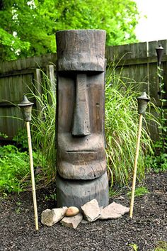 a wooden totem sitting in the middle of a garden