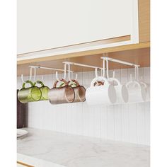 mugs are hanging on the kitchen rack above the sink