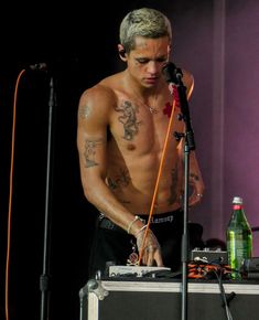 a shirtless man standing in front of a microphone