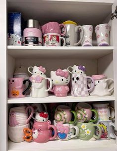 hello kitty mugs are on shelves in a cupboard