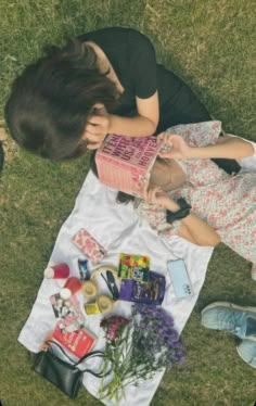 a woman sitting on top of a white blanket next to flowers and other items in front of her