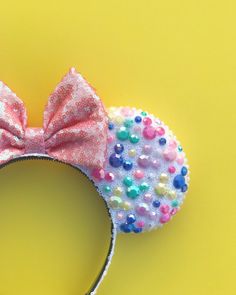 a minnie mouse ears with multicolored sequins and a bow on it