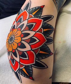 a close up of a person's leg with tattoos on it and an orange flower