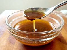 a spoon pouring sauce into a glass bowl