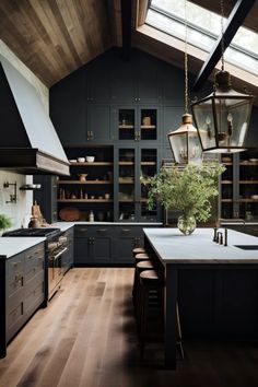 a large kitchen with wooden floors and black cabinets, along with an island in the middle